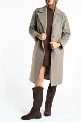 Tapado largo de corte oversize en color beige, con solapas clásicas y cierre frontal con botones. Presenta un diseño minimalista y elegante, ideal para un look sofisticado.