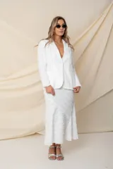 Blazer de corte sastre en color blanco, confeccionado en crepé satén con detalles de flecos de seda en toda la prenda. Presenta solapas clásicas, cierre frontal con botón de nácar y dos bolsillos laterales tipo ojal.