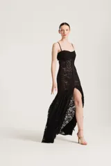 Vestido largo negro de encaje transparente, con tirantes finos, escote recto y botonadura frontal.
