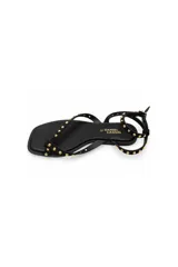 Sandalia plana Daniel Cassin de color negro, con diseño de tiras delgadas decoradas con tachas metálicas doradas, formato de dedo y pulsera ajustable al tobillo con hebilla.