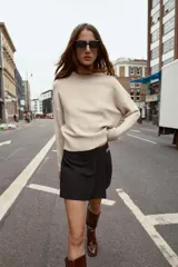 Bermuda de tiro alto color negro, con diseño de tablas frontales y detalle de eslabones metálicos dorados en la cintura. Cuenta con cierre lateral oculto.