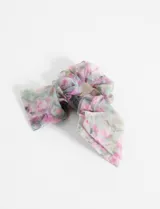 Scrunchie con estampado floral en tonos rosa, verde y blanco, confeccionado en tela de poliéster transparente. Incluye lazos largos que se pueden atar o dejar sueltos.