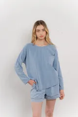 Remera de manga larga color celeste, de diseño holgado, escote redondo y bolsillo aplicado en el pecho.