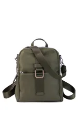 Mochila de tamaño mediano, color beige claro, con cuerpo principal de tela impermeable y detalles en simil cuero liso en la parte inferior y correas. Presenta un asa superior corta y correas ajustables para llevar al hombro o cruzada. Cuenta con un bolsillo frontal con cierre y un detalle decorativo de correa con hebilla metálica rectangular.