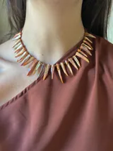 Collar corto con bastones de nácar teñidos en tonos anaranjados y mostacillas doradas. Se cierra con cadena de acero quirúrgico y gancho para regular el largo.