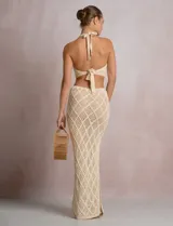 Top crop de tejido calado beige, con escote halter y patrón geométrico de rombos.