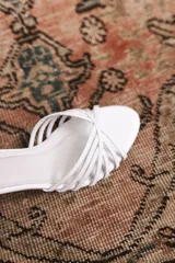Sandalia de taco cuadrado bajo color blanco, con múltiples tiras finas cruzadas en el empeine y tira ajustable en el tobillo con hebilla dorada.