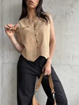 Chaleco color tostado de lino liviano con bordado de palmeras en la terminación y corte recto. Cierre frontal con botones.