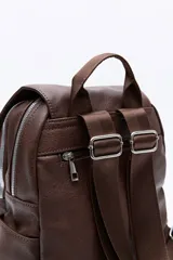 Mochila negra de cuero sintético con solapa y cierre de cordón con dos flecos decorativos con cuentas plateadas. Cuenta con tres compartimentos principales, bolsillos internos adicionales, dos bolsillos laterales y un bolsillo trasero con cierre. Tiene un asa superior fija y dos correas regulables en la espalda.