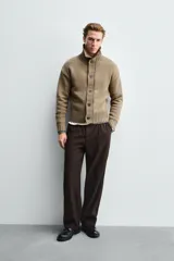 Chaqueta de punto de corte relajado, color marrón, con cuello subido, manga larga y cierre frontal de botones. Presenta acabados en rib en puños y ruedo.