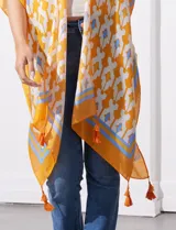 Kimono tejido con estampado abstracto en tonos azules, blancos y violetas. Tiene terminación de ruedo con borlas.