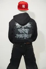 Hoodie negro oversize de algodón con capucha y pasamontañas desmontable con cierre. Presenta estampa en plastisol en el pecho y en ambas mangas.