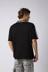 Remera de corte oversize color negro, con cuello redondo y detalle de costura en forma de X en el frente.