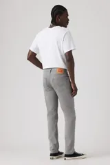 Pantalón de corte slim fit confeccionado en sarga de algodón con elastano, color gris. Presenta diseño clásico de cinco bolsillos, cierre de botón y cremallera, y costuras reforzadas.