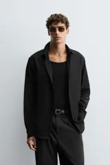 Camisa blanca de manga larga con cuello italiano y cierre frontal de botonadura. Corte regular fit.