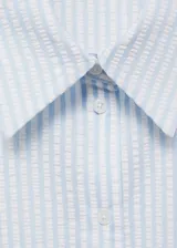 Camisa sin mangas con cuello clásico, cierre frontal con botones y diseño a rayas verticales en tonos celeste y blanco.