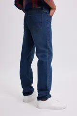 Pantalon de jean de corte clasico en color azul oscuro, con cierre de boton y cremallera, y bolsillos laterales y traseros.