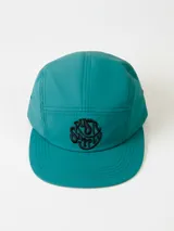 Gorro tipo cap de cinco paneles color verde azulado, con visera plana y logo de la marca bordado en negro en el frente.