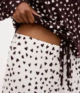 Pijama largo compuesto por blusa de manga larga con lazo ajustable en el bajo y pantalón tipo jogger con cintura elástica. Presenta un diseño bicolor con estampado de mini corazones en toda la prenda.