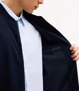 Campera estilo bomber de color negro, confeccionada con tejido repelente al agua. Posee cuello semi alto, cierre frontal con cremallera, bolsillos laterales y puños y dobladillo elastizados. Marca Marfinno.