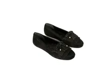 Mocasín de gamuza color negro con detalle de flecos y lazo frontal con herrajes metálicos dorados. Cuenta con interior forrado en cuero y suela de goma flexible.