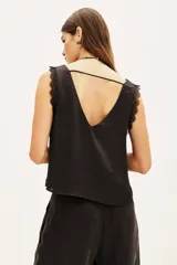 Top negro de poliéster con escote en V, tirantes con detalle de encaje y corte holgado.