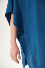 Poncho celeste de tejido de punto con cuello redondo y terminación desflecada.