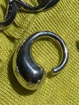 Anillo plateado de metal con forma redondeada y diseño chunky.