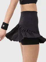 Falda deportiva tipo skort color negro, con cintura alta y diseño de pliegues en el ruedo. Incluye short integrado con bolsillo lateral.