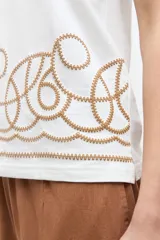 Musculosa cruda de corte recto y sin mangas, con cuello redondo y diseño estampado en relieve en el borde inferior.