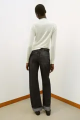 Jeans de tiro alto color negro lavado, con cintura cruzada, cinco bolsillos y pernera recta. El bajo está acabado en vuelta y tiene cierre frontal cruzado con cremallera y botones.