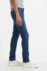 Pantalón de jean azul oscuro, corte skinny taper con tiro medio.