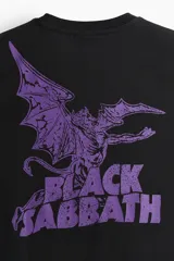 Remera de algodón color negro con cuello redondo y mangas cortas. Presenta un estampado frontal con el logo de la banda Black Sabbath en color violeta.