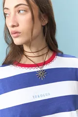 Remera de algodón con diseño de rayas horizontales azules y blancas, cuello redondo en color rojo con detalle de costura en zigzag y bordado frontal con la palabra Yorugua.