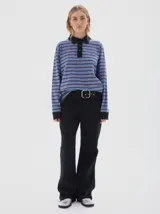 Chomba de manga larga con diseño a rayas horizontales en tonos azul y gris. Presenta cuello polo y cartera de botones en color negro, con puños negros y bordado pequeño en el pecho.