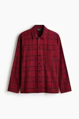 Pijama de dos piezas confeccionado en franela de algodón. Incluye una camisa de manga larga con cuello inglés, botones frontales y bolsillo en el pecho, junto con un pantalón de corte recto con cintura elástica y cordón ajustable.