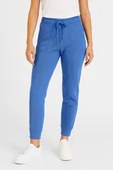 Pantalón deportivo azul de tejido acanalado, con cintura elástica ajustable mediante cordón, bolsillos delanteros y puños elastizados en los tobillos.