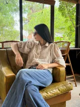 Camisa de corte oversize con estampado de rayas verticales, cuello clásico y mangas abullonadas con puños elásticos.