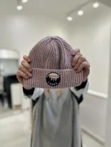 Gorro de lana color lila con parche circular con diseño de montañas y el texto "Lanka" en el borde.