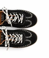 Championes de cuero color negro con pespuntes visibles en contraste de color blanco, cordones bicolor y detalles en tono tostado.