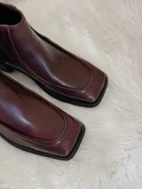 Botas cortas color bordó con punta cuadrada, suela negra y cierre lateral.