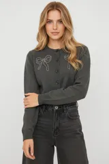 Cardigan de punto color gris oscuro, con cuello redondo, cierre frontal con botones y detalle de moños bordados en el pecho.