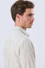 Camisa de lino rayada de manga larga, con cuello camisero, cierre frontal de botones y bordado sutil en el pecho.