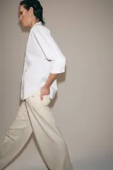 Camisa de algodón con cuello redondo y escote en pico, mangas tres cuartos con puños y bajo asimétrico redondeado.