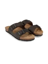 Sandalias de cuero marrón oscuro con doble tira ajustable mediante hebillas metálicas, plantilla anatómica con base de corcho y suela de goma estriada.