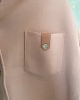 Camisa de lana color rosado, de corte oversize, con mangas largas, bolsillos frontales con solapa y cierre de botones.