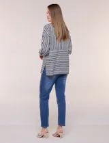 Camisa de rayón con estampado de rayas blanco y negro, de corte fluido, cuello con solapa, cierre frontal con botones y mangas largas regulables.