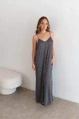 Vestido largo de jersey con estampado de lunares blancos sobre fondo negro. Presenta breteles finos, escote en V y un calce holgado y fluido.