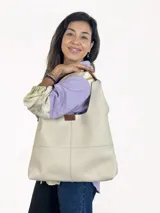 Bolso tipo tote de cuero color crema, con paneles rectangulares cosidos y etiqueta de cuero con logo en el frente.