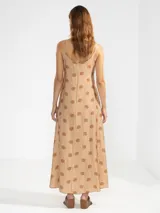 Vestido largo de corte fluido con escote en V profundo y finos breteles. Presenta un estampado animal print combinado con rayas y un detalle decorativo de flor en cobre en el centro del escote.